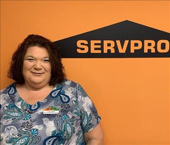 Female employee standing against SERVPRO wall with top