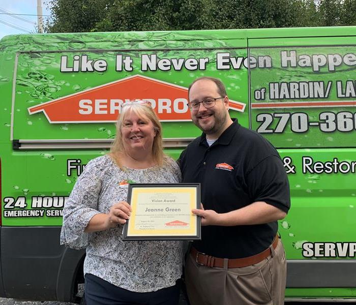 Female and Male Employee standing in front of SERVPRO van