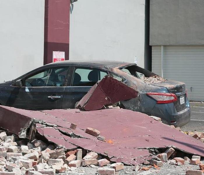 Earthquake damage. Car with a busted window surrounded by rubble. 
