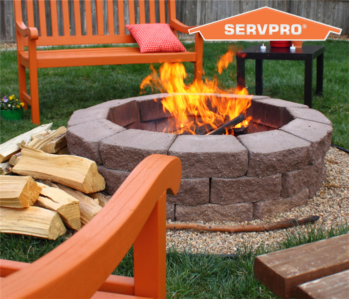 A lit firepit in the middle of a circle of orange outdoor furntiture. Orange SERVPRO logo in top right corner